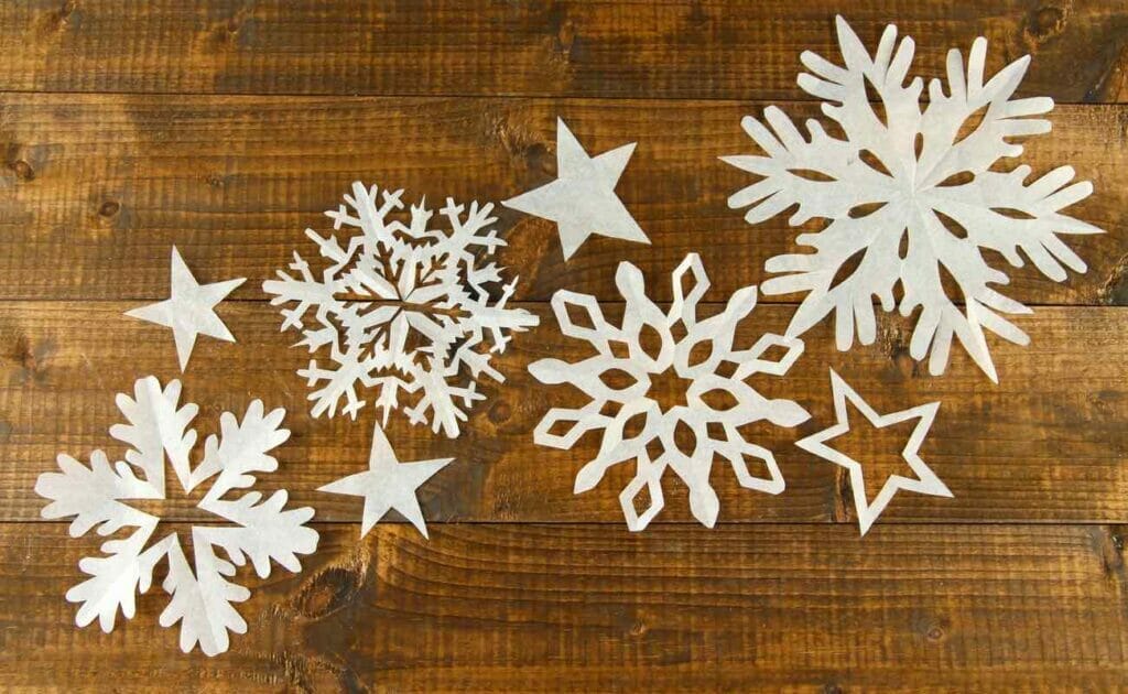  Paper snowflake cutouts on a wooden table.