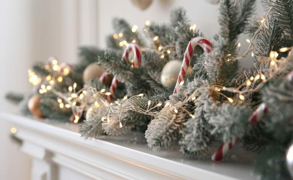  Close-up of a Christmas garland on a mantel with fairy lights, pine cones and candy canes.