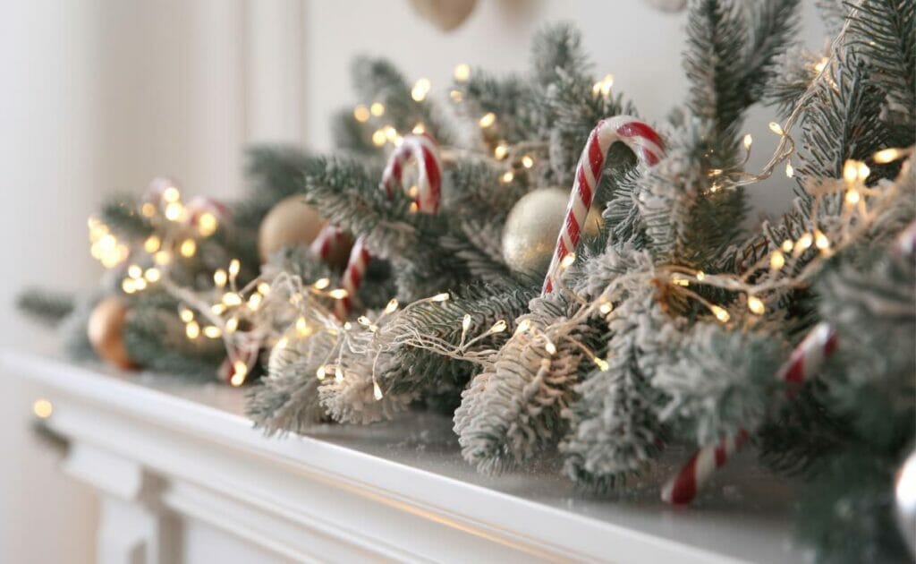 Close-up of a Christmas garland on a mantel with fairy lights, pine cones and candy canes.