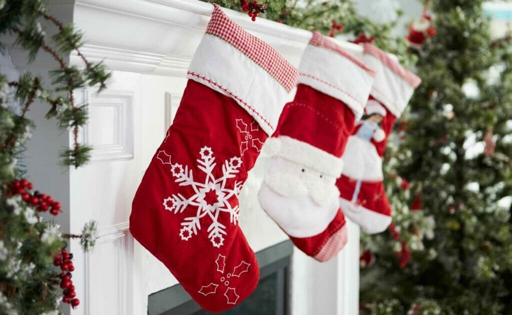 Three red and white Christmas stockings hanging on a white mantel.