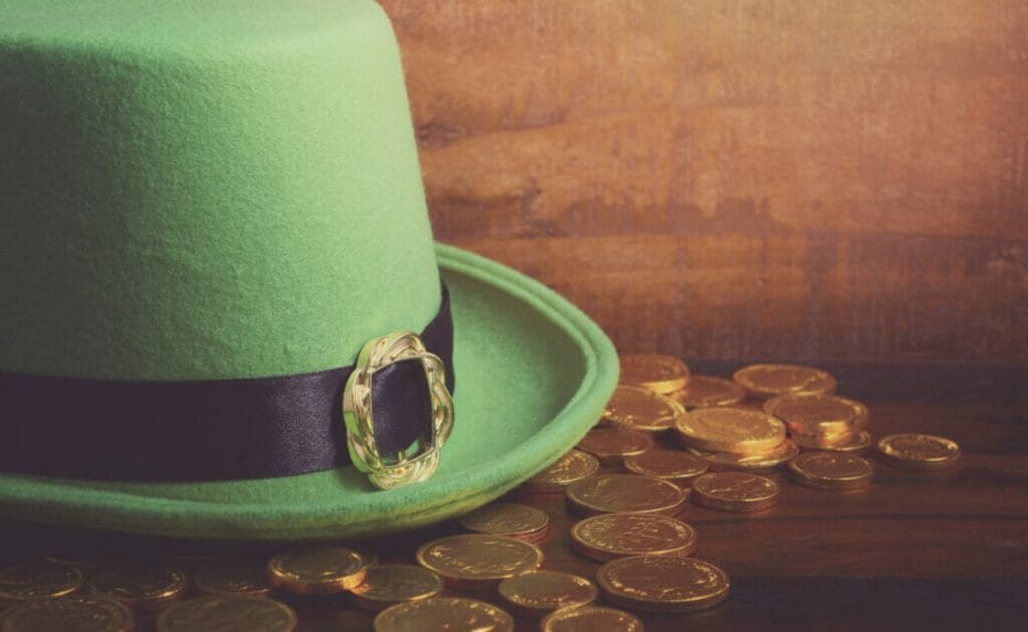 A green leprechaun hat with gold coins on a table.