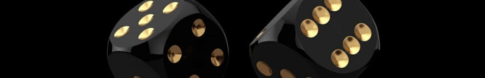 A pair of black and gold dice rolling against a black background