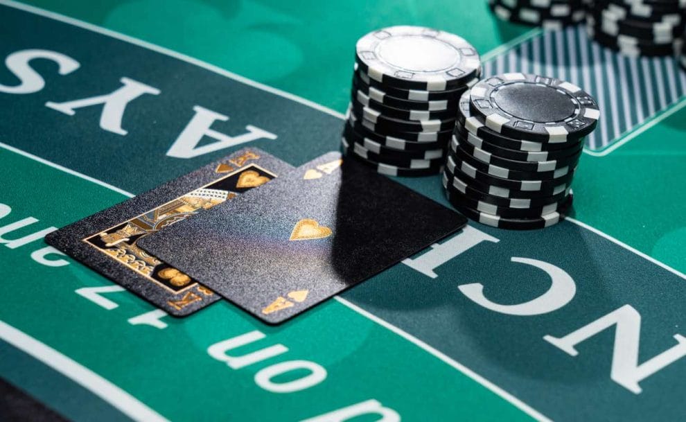 Closeup of a blackjack table at a casino with two black playing cards and two stacks of black chips