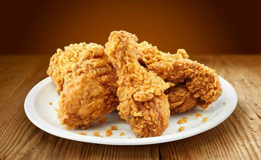 Fried chicken placed on a white plate and wooden table.