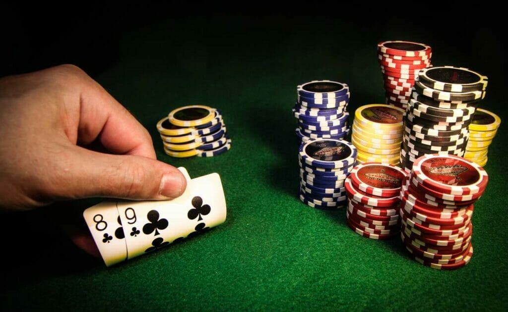 A hand showing two playing cards with casino chips in the frame.