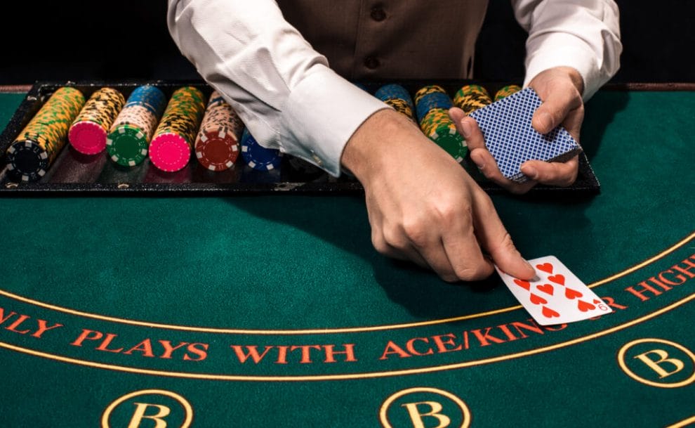 Close up of Hold’em dealer with playing cards and chips on green table.