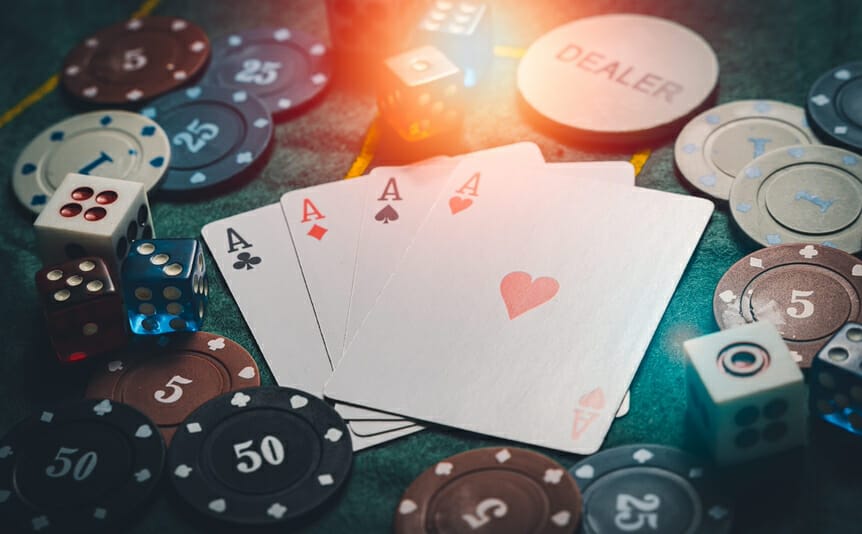 Four aces, dice and chips on a poker table.