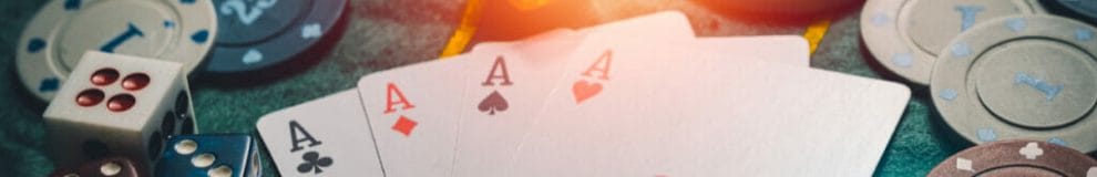 Four aces, dice and chips on a poker table.