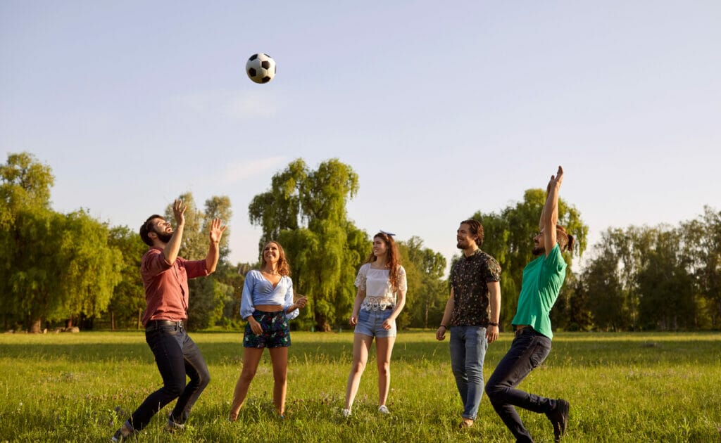 A group of friends play with a soccer ball on a field.