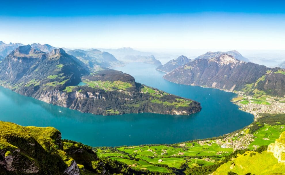 A beautiful view of a blue river and green mountains in Bürgenstock, Switzerland.