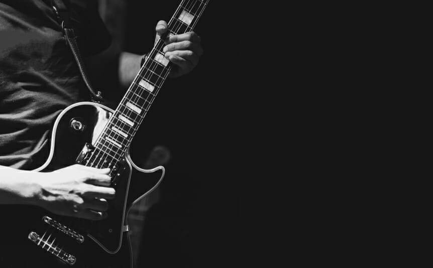 Black and white image of a person playing the guitar.