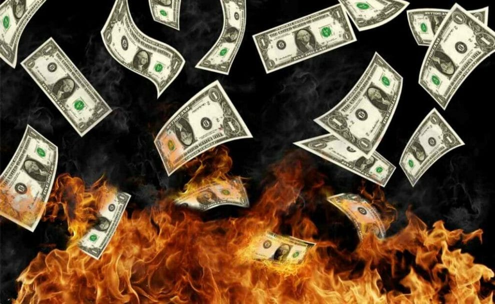 Burning dollar banknotes against a black background.