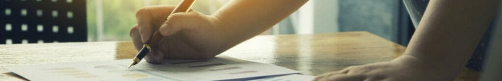 A person writes on some graphs on a desk.