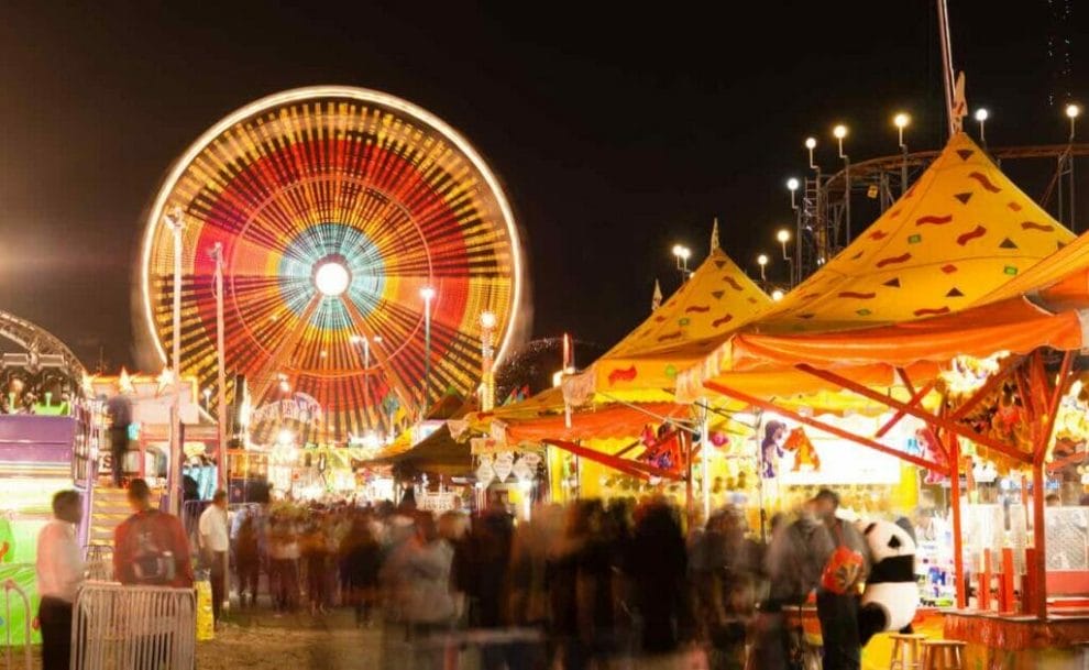 A Ferris wheel and carnival festivities lit up during the state fair.