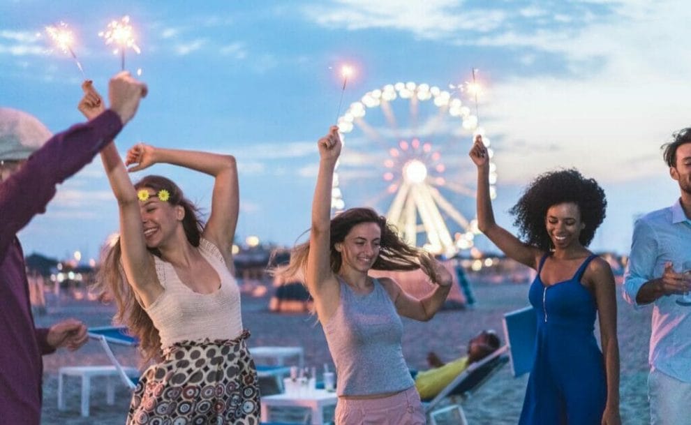 Friends dancing on a beach with a Ferris wheel in the background