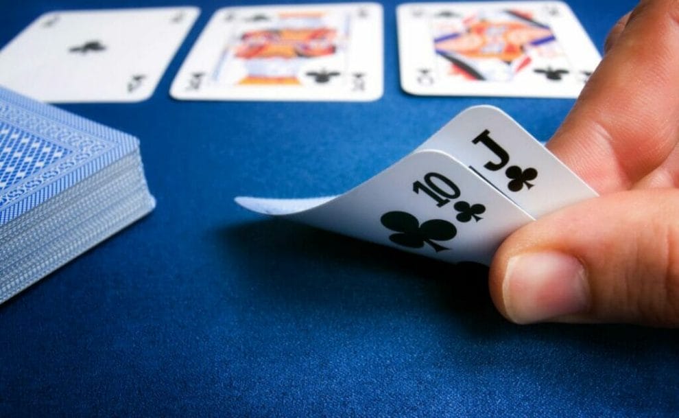 A poker player checks their hole cards during a game.