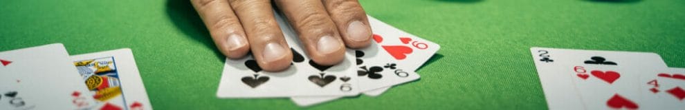 A man covers his poker cards with his fingers.