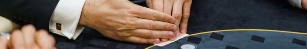 A man protects his hole cards while he looks at them during a poker game.