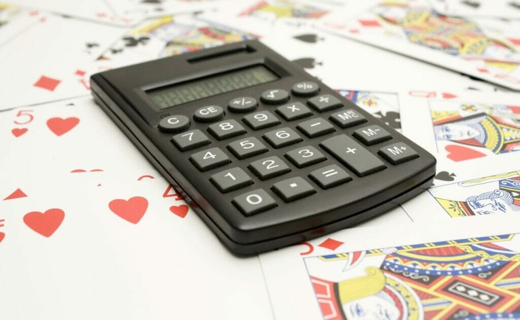 A calculator placed on top of playing cards scattered on a table.
