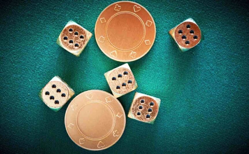 Gold casino chips and dice on a green felt table.