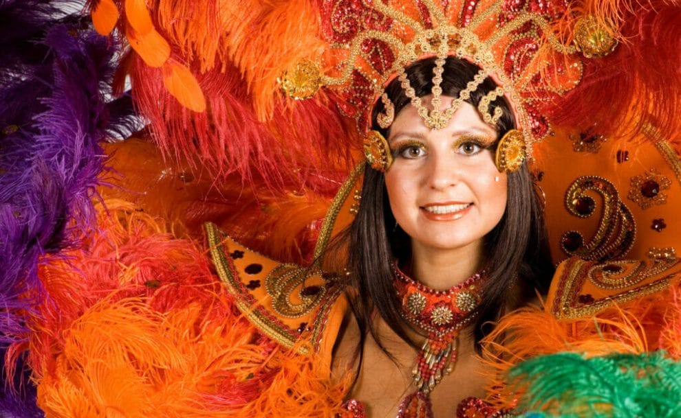 A woman in a bright orange carnival headdress and costume.