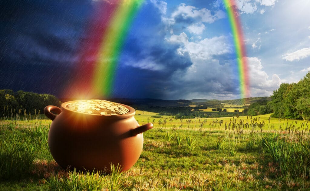 A jackpot of gold at the end of the rainbow with Irish countryside in the background.