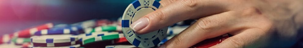A woman holds a poker chip in between her fingers.