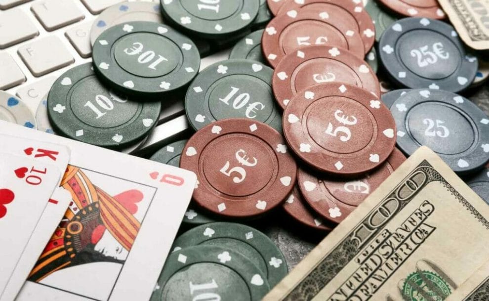 Playing cards, poker chips and a hundred dollar bill on a computer keyboard.