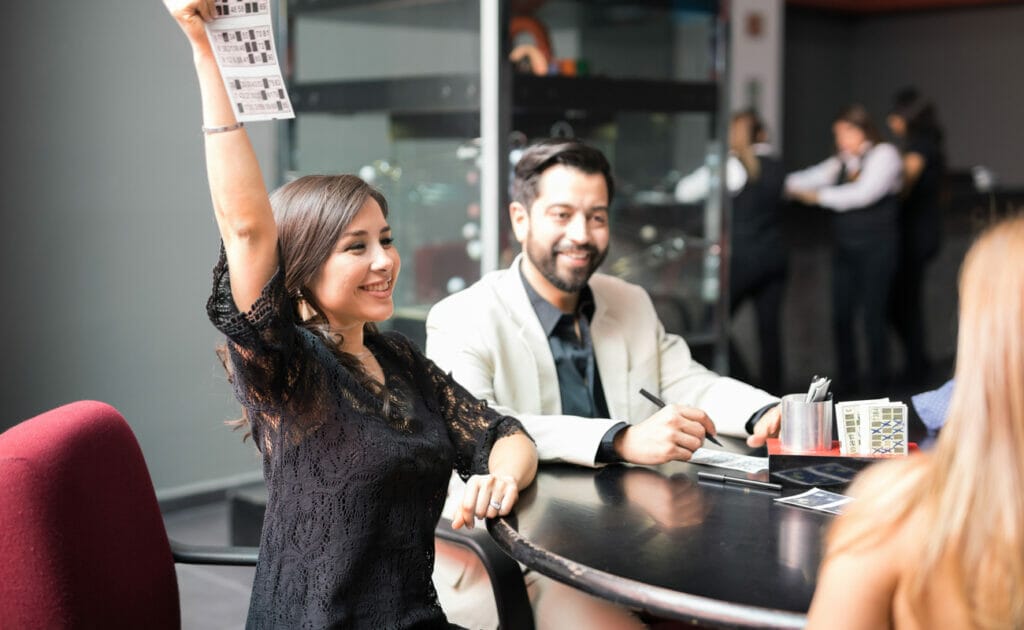 A woman raises her bingo card in an office bingo game.