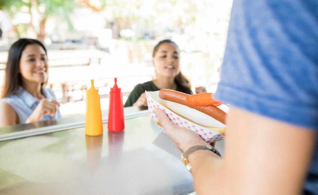 Two women wait for a hot dog at a food truck.