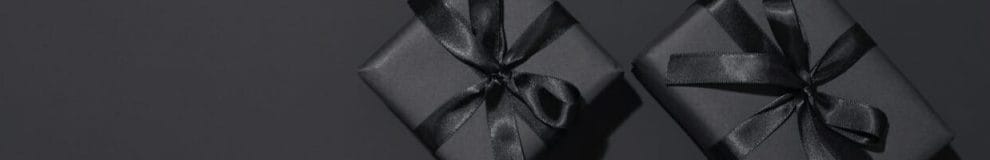 Top view of two black wrapped gift boxes on a black background.