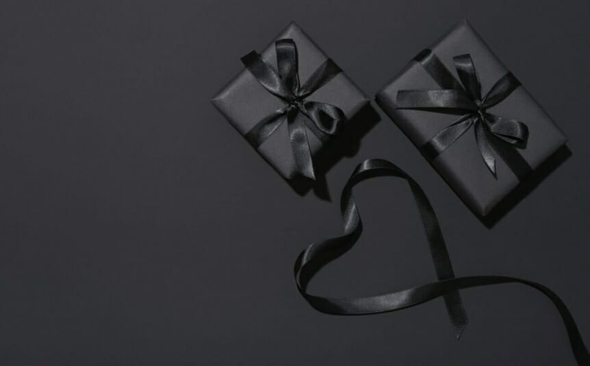 Top view of two black wrapped gift boxes on a black background.