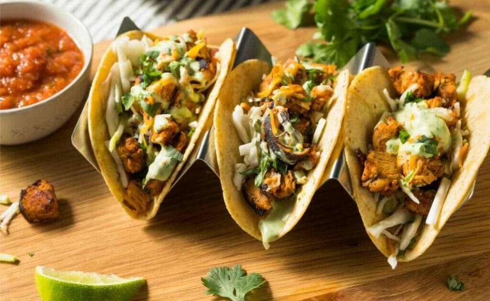 Close-up of three tacos on a chopping board.