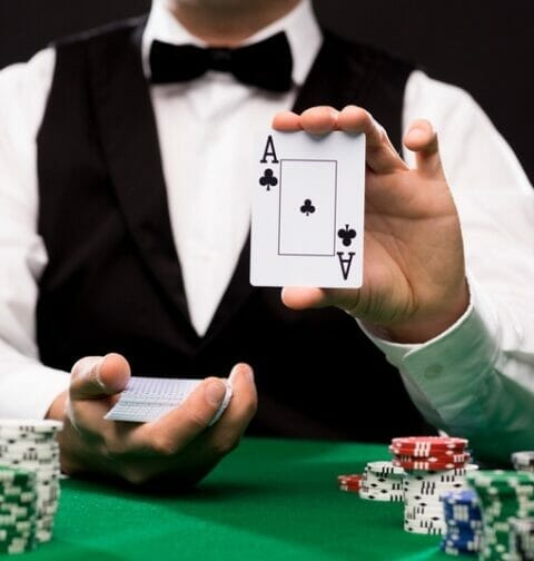 A professional poker dealer holding up an ace.
