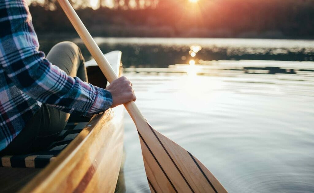 A person paddling a canoe on a lake.
