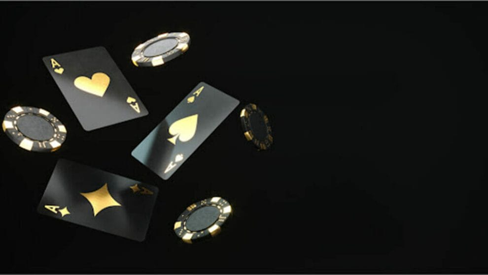 Black and gold playing cards and poker chips against a black background.
