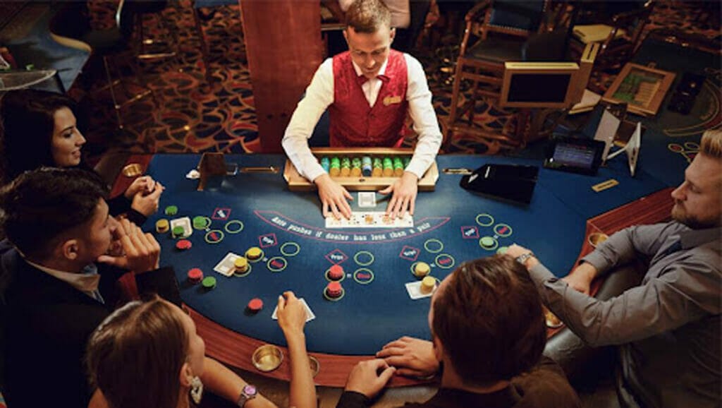 Poker players and a dealer, playing at a blue felt table.