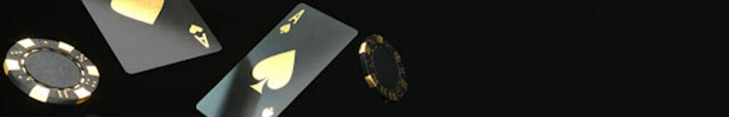 Black and gold playing cards and poker chips against a black background.