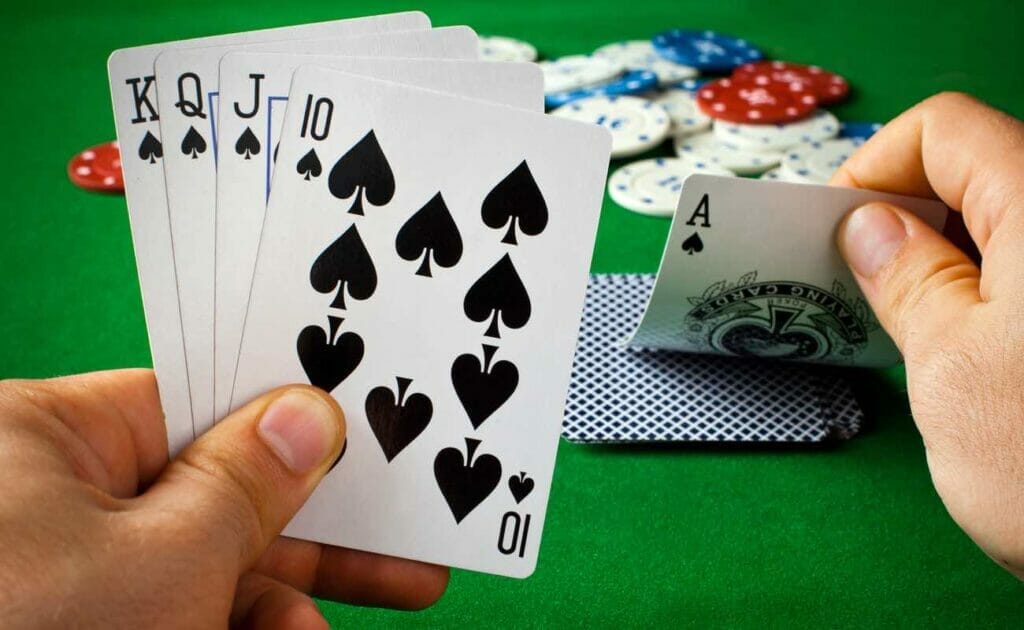 A player picks up an Ace from the table to complete a Royal Flush hand.
