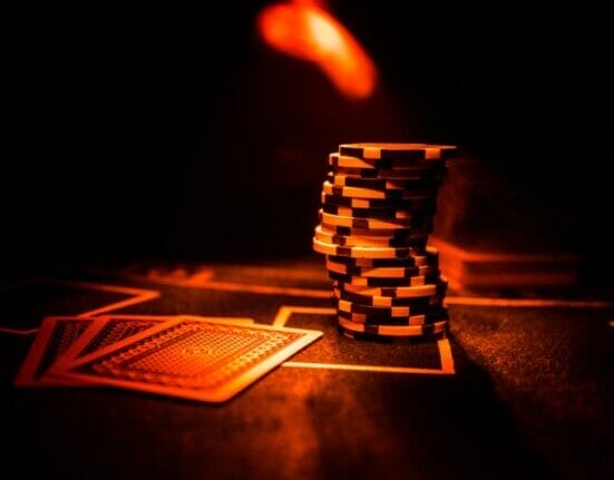 Cards and chips on a poker table in a red light.
