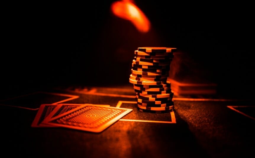 Cards and chips on a poker table in a red light.