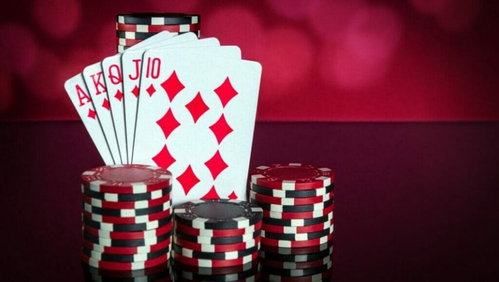 Poker hand showing a royal flush with poker chips stacked on a table.