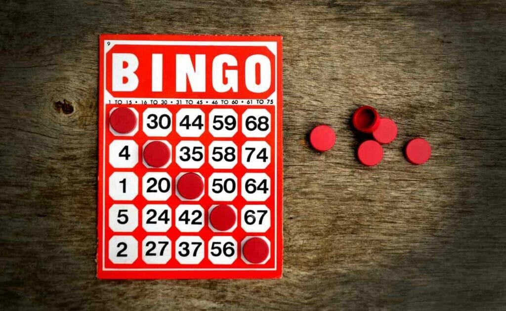 A red 75-ball bingo card on a wooden table with red daubers forming a winning line.