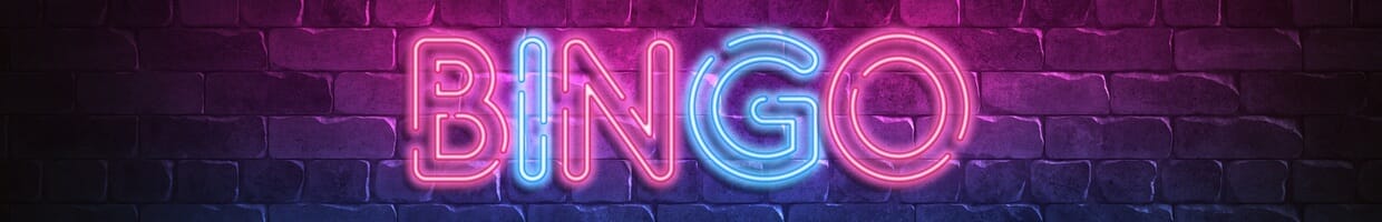 A neon-lit “BINGO” sign hanging on a brick-face city wall.