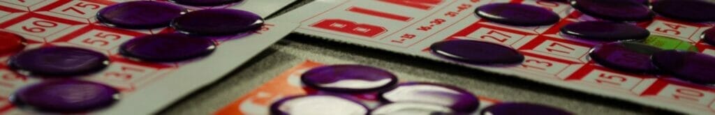 Bingo cards on a table with markers on top of them.