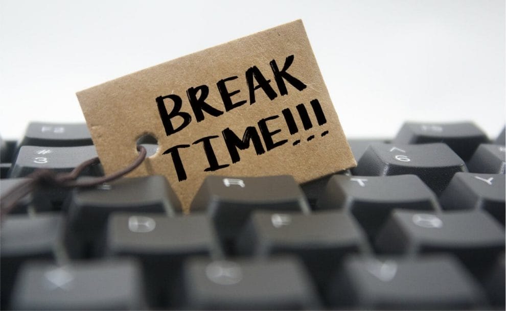 “Break time!!!” written on a piece of paper nestled into a computer keyboard.