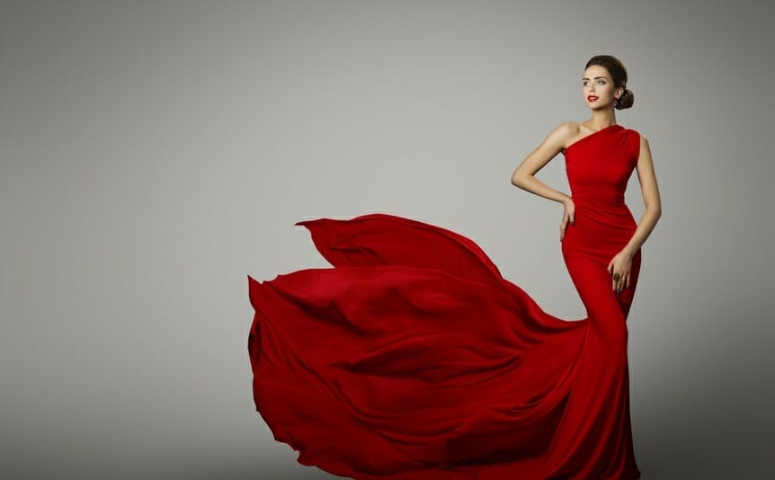 A woman in a beautiful red dress photographed against a gray background.