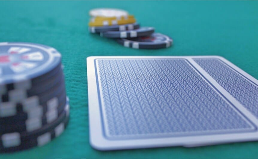 Two cards face down on a poker table with some chips.