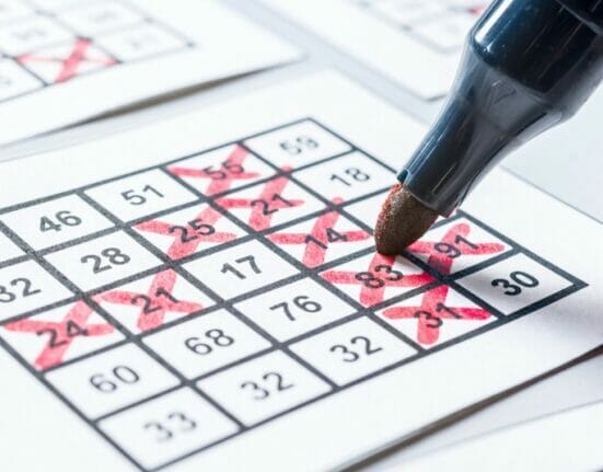 A person crosses out bingo squares with a red marker.
