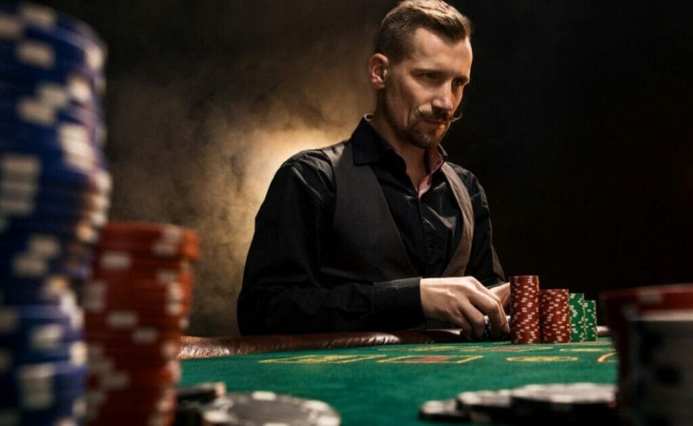 A man at a poker table considers his cards.